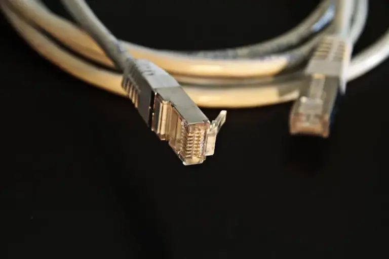 Gray shielded Ethernet patch cable with metal-jacketed RJ45 plugs coiled on a black surface