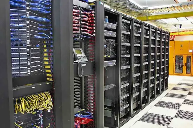 Server racks with blue, red and yellow patch cables and a desk phone mounted on one cabinet