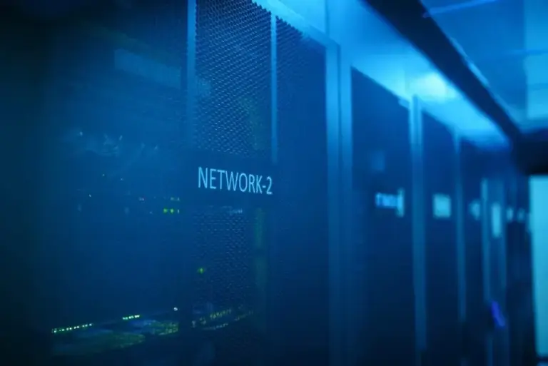 Server cabinet with a mesh door and network label in a blue-lit data center aisle