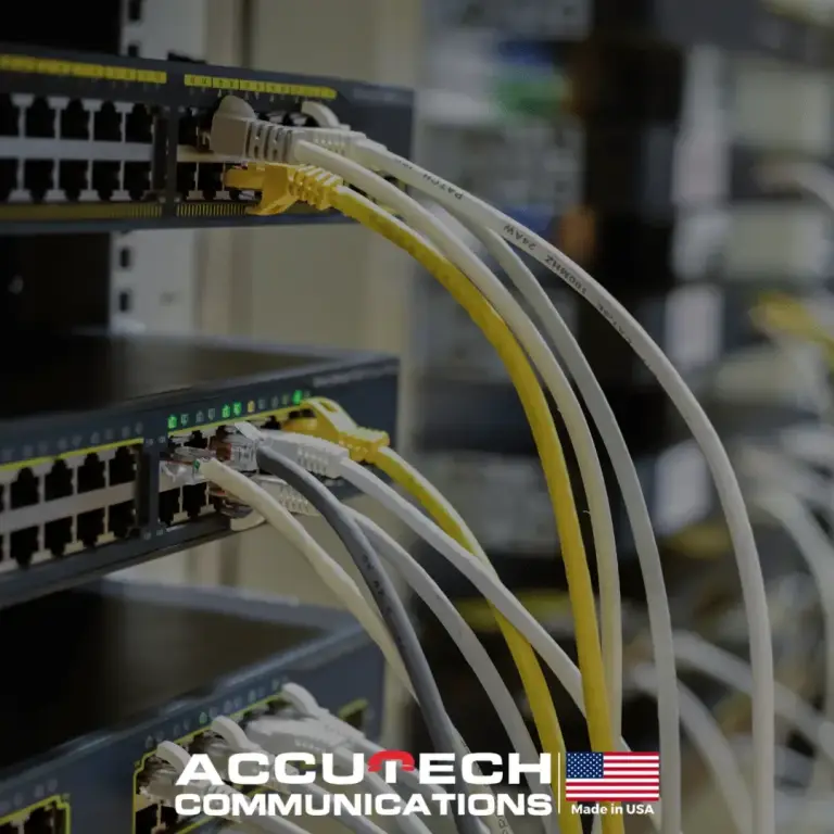 White, gray and yellow patch cables connected to stacked network switches with green port lights