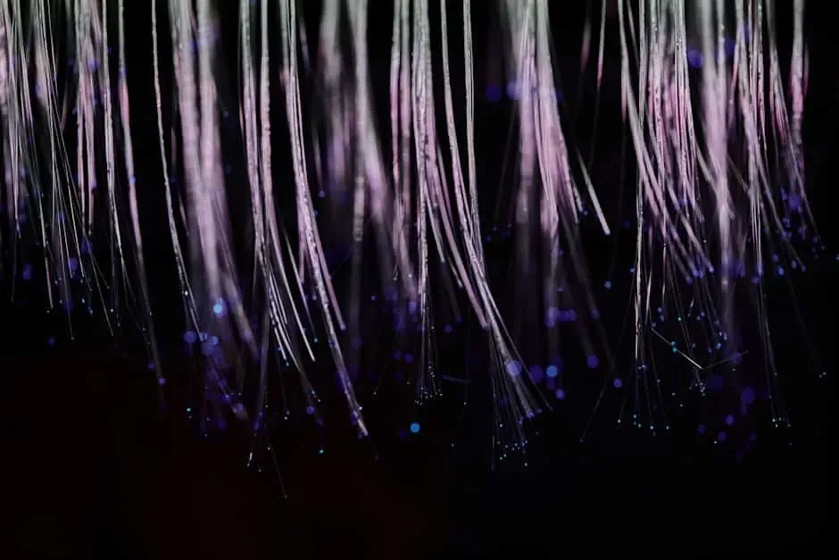 Close-up of fine fiber optic strands hanging down with glowing tips against a dark background