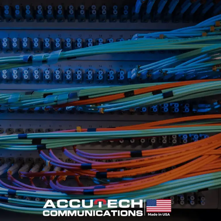 Rack of fiber patch panels with bundled aqua and orange patch cords under blue light
