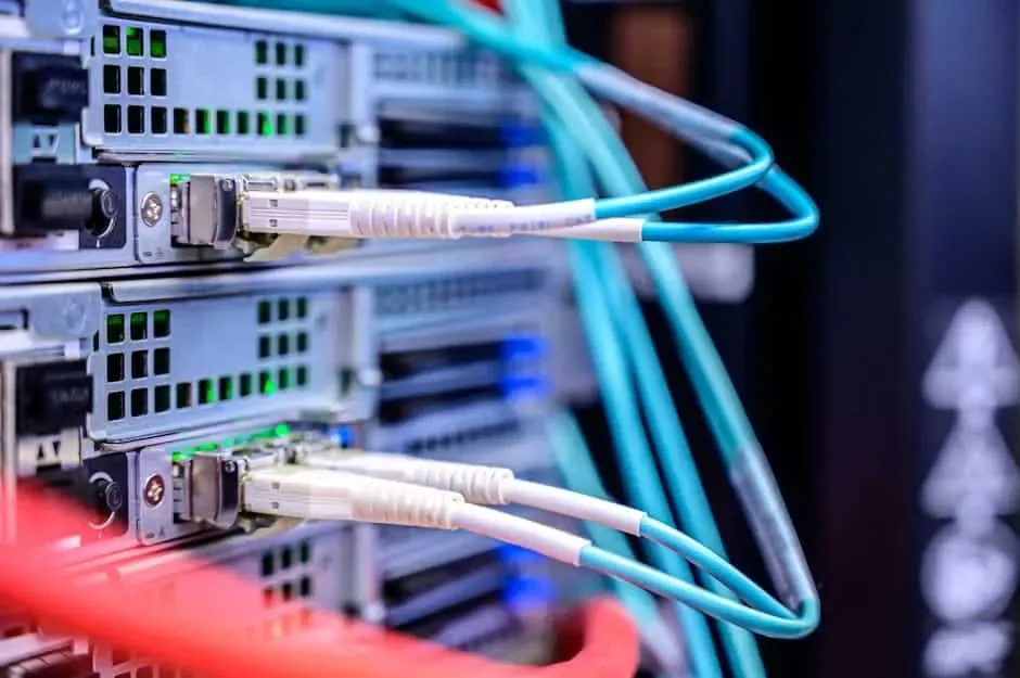 Aqua fiber patch cords with white connectors plugged into ports on rack-mounted servers