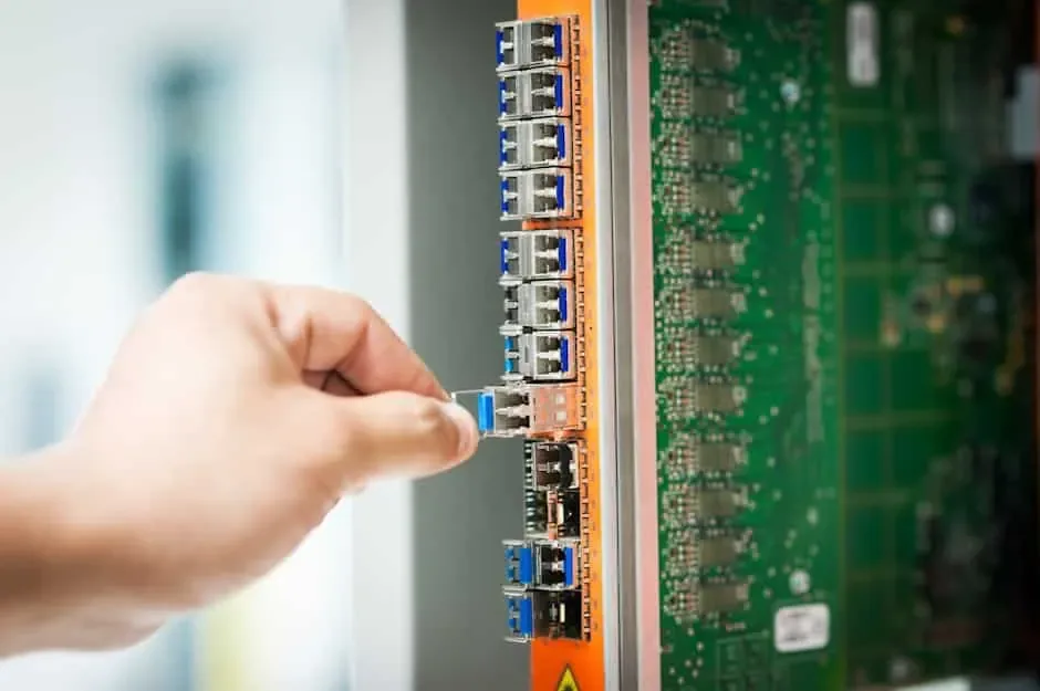 Hand removing a small plug-in module from a column of ports on a network line card