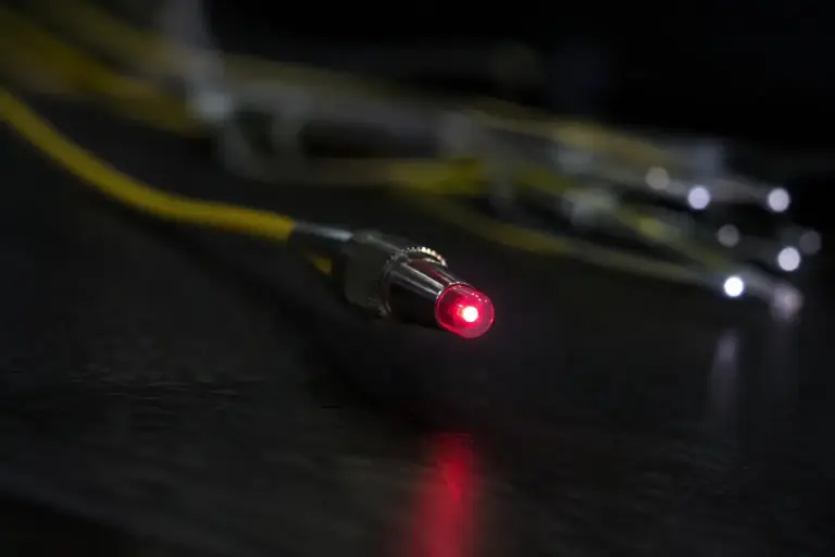 Macro of a fiber optic connector tip glowing with a point of red light