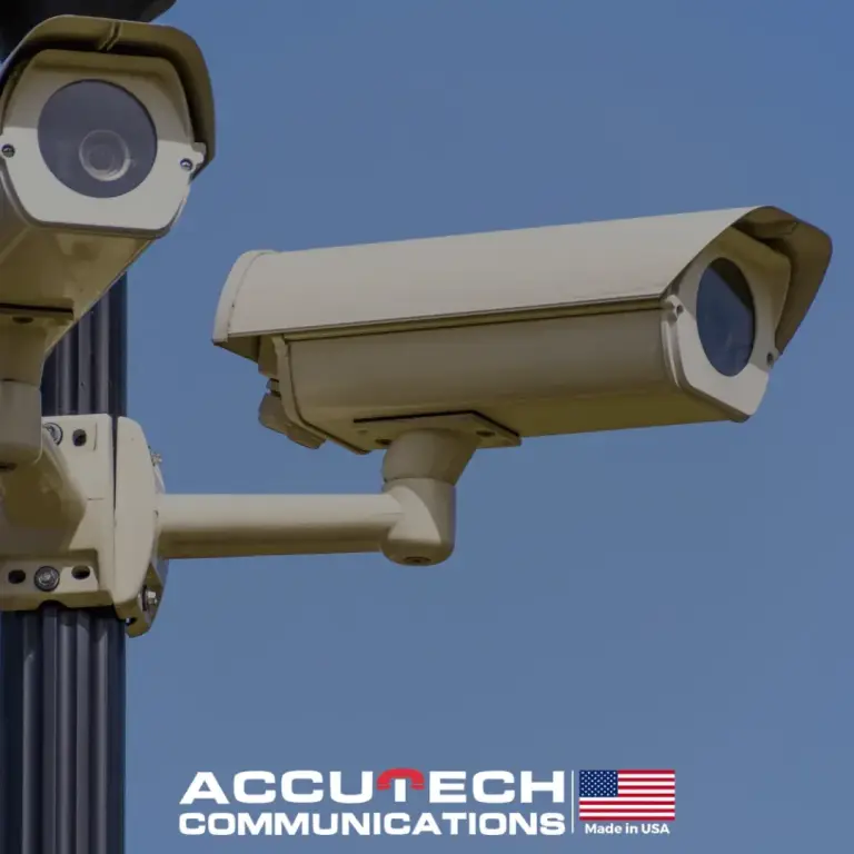 Two outdoor security cameras mounted on a pole against a blue sky