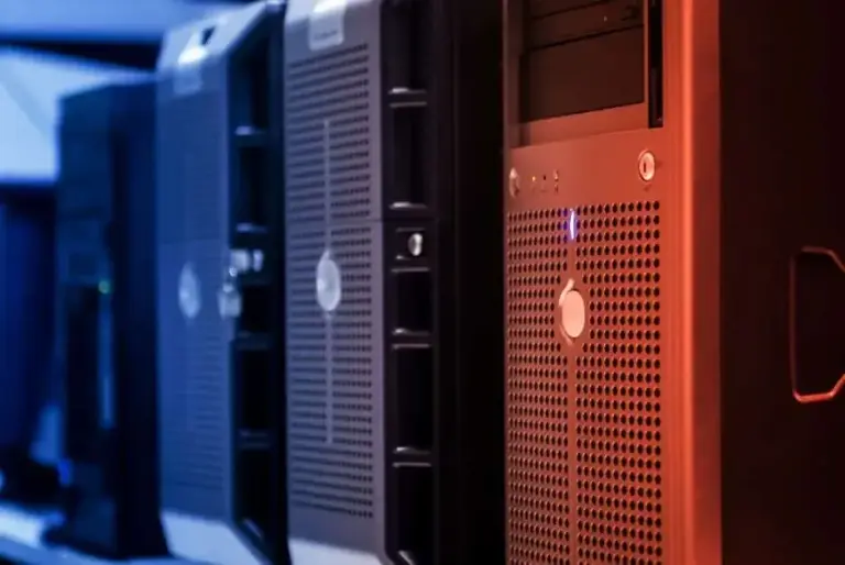 Row of tower servers with perforated metal fronts lit in blue and orange light