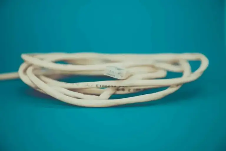Coiled beige Ethernet cable with an RJ45 plug resting on a teal background