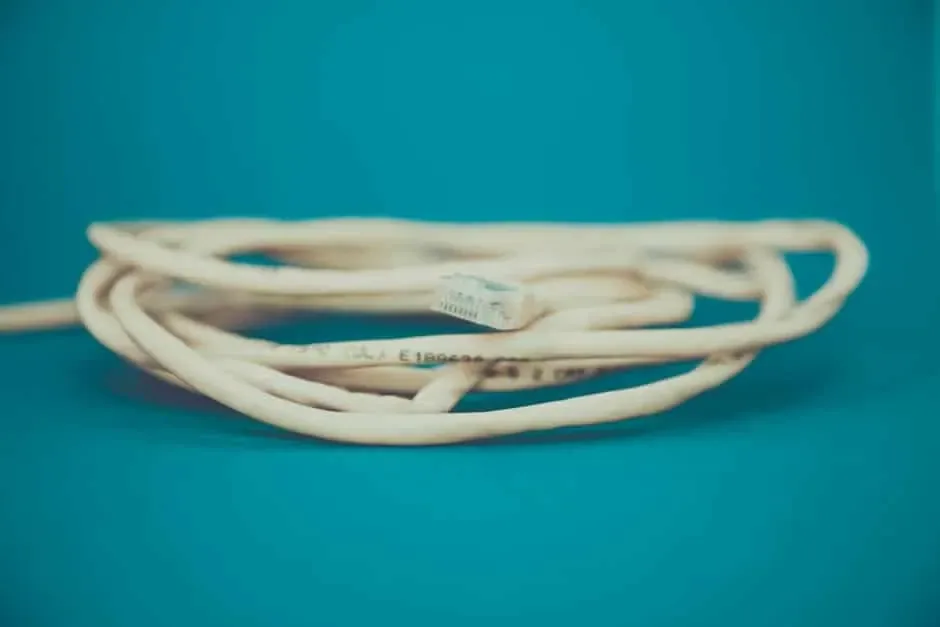 Coiled beige Ethernet cable with an RJ45 plug resting on a teal background