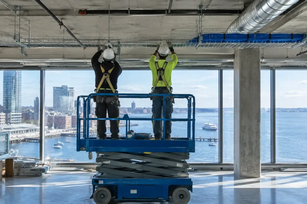 Technicians hanging cable tray in a new waterfront office with harbor views
