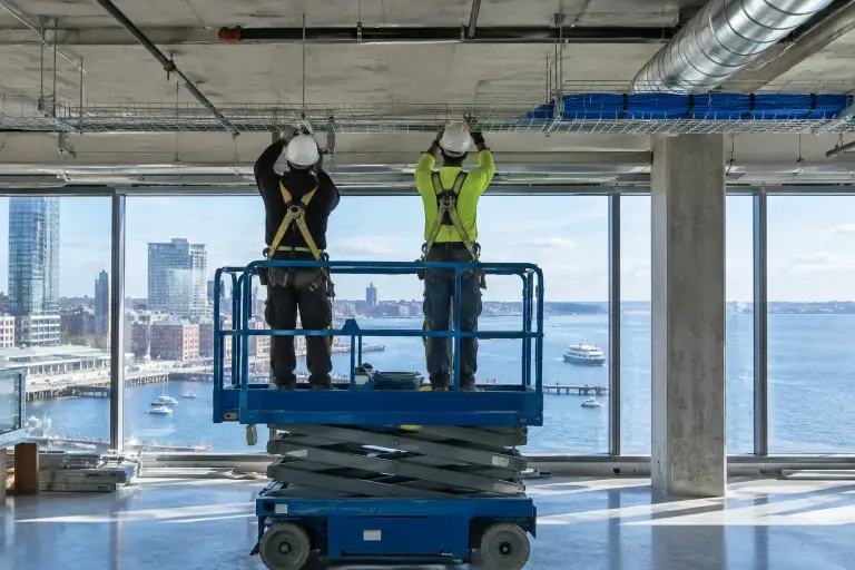 Technicians hanging cable tray in a new waterfront office with harbor views