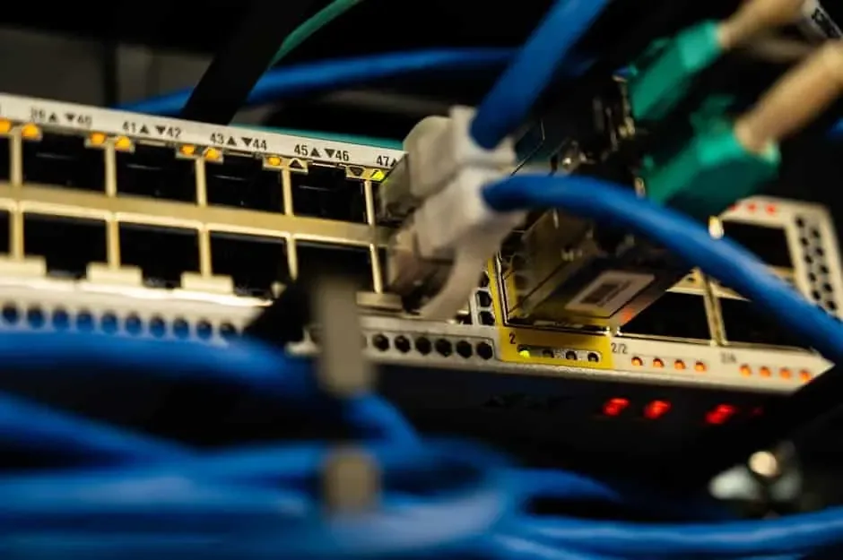 Blue network cables and a fiber module plugged into a switch with glowing port lights