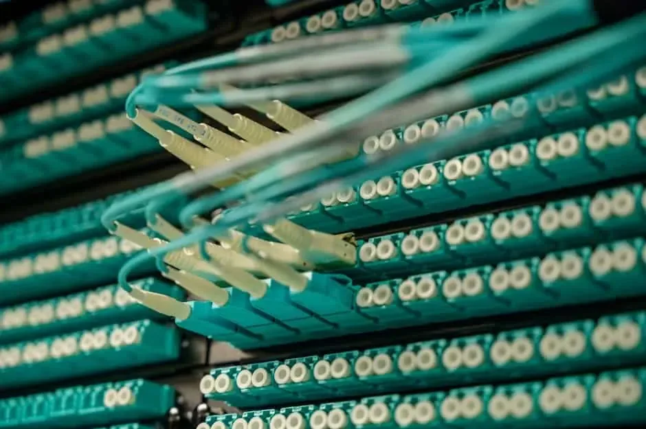 Aqua fiber patch cords plugged into rows of white-capped fiber adapter panels