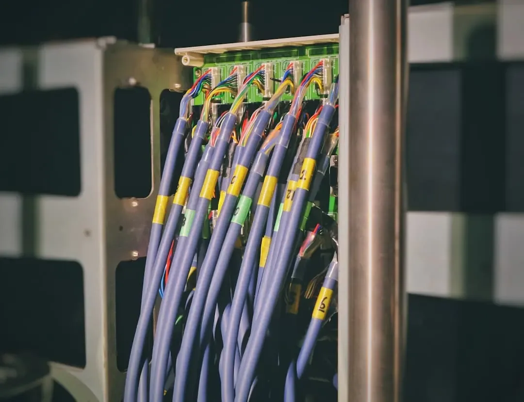 Purple cables with yellow number labels connected to a green terminal board in a rack