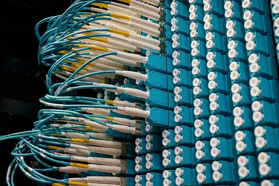 Aqua fiber patch cords with yellow-banded connectors plugged into a dense fiber adapter panel