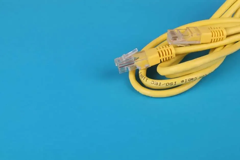 Coiled yellow Ethernet cable with two RJ45 plugs on a bright blue background