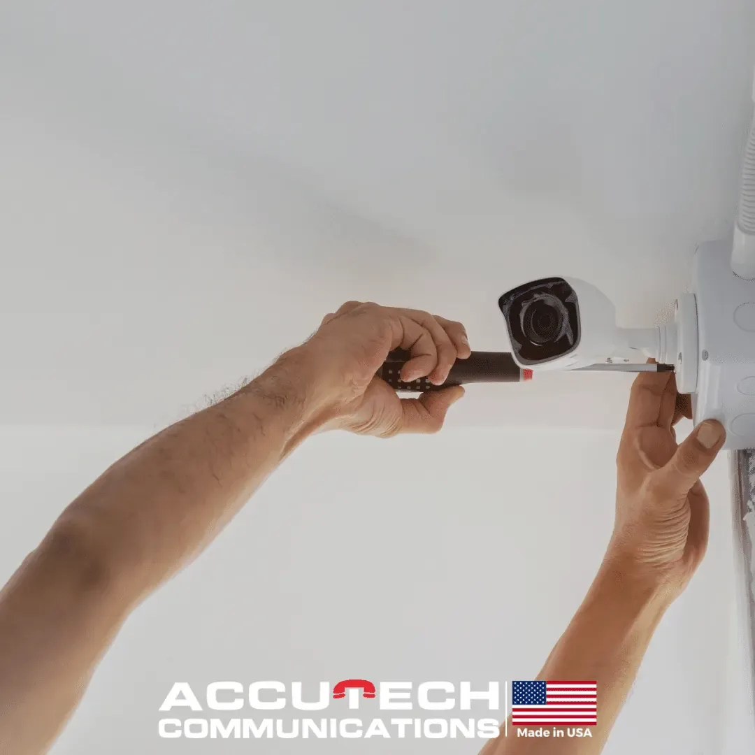 Hands using a screwdriver to mount a white bullet camera to a ceiling junction box