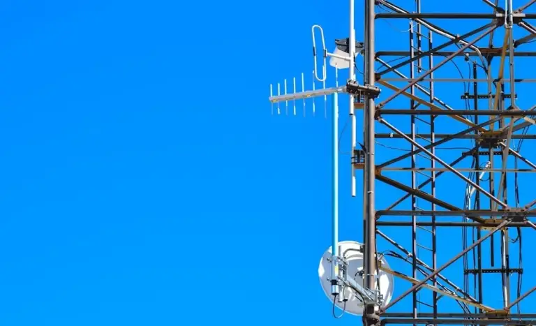 Antennas and a microwave dish mounted on a steel lattice tower against blue sky