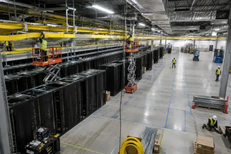Data hall under construction with half the cabinet rows installed and crews on lifts
