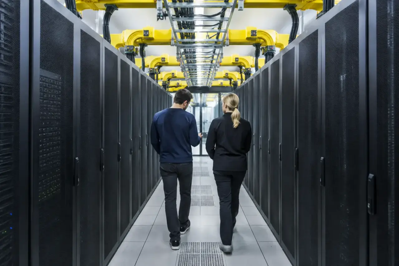 Two engineers walking down a data center aisle under yellow fiber raceway