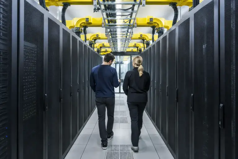 Two engineers walking down a data center aisle under yellow fiber raceway